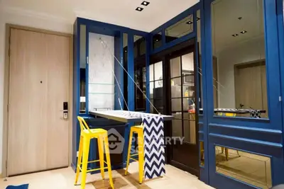 Stylish modern interior with blue accents and yellow bar stools in a compact living space.