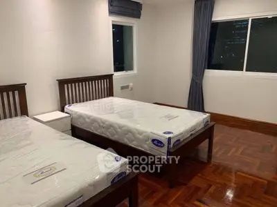 Spacious bedroom with twin beds and city view, perfect for urban living.