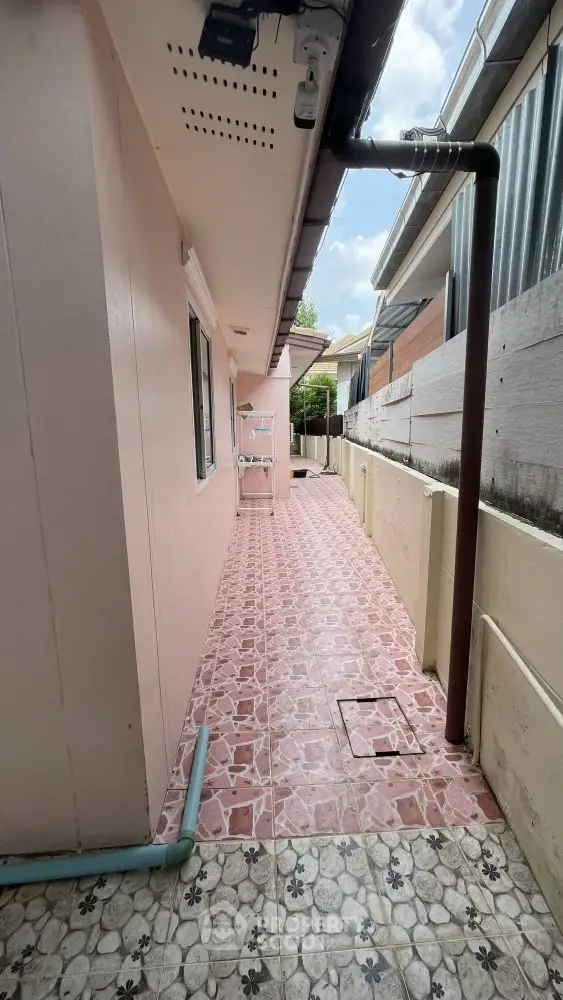 Charming narrow exterior walkway with pink tiles and white accents, perfect for cozy outdoor moments.