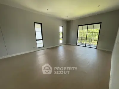 Spacious empty living room with large windows and balcony access, perfect for customization.