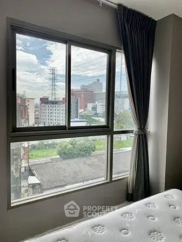 Bright bedroom with large window offering stunning city view and modern decor.