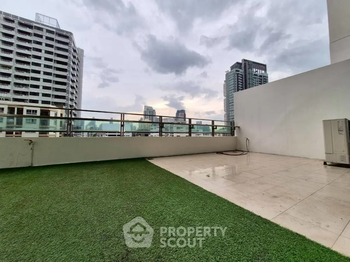 Spacious rooftop terrace with city skyline views and artificial grass flooring.