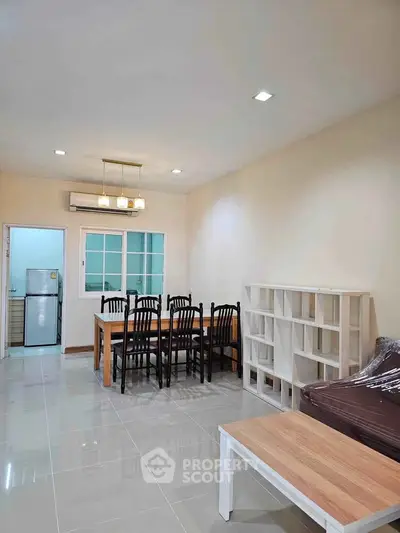 Spacious living room with dining area and modern furniture in a well-lit apartment.