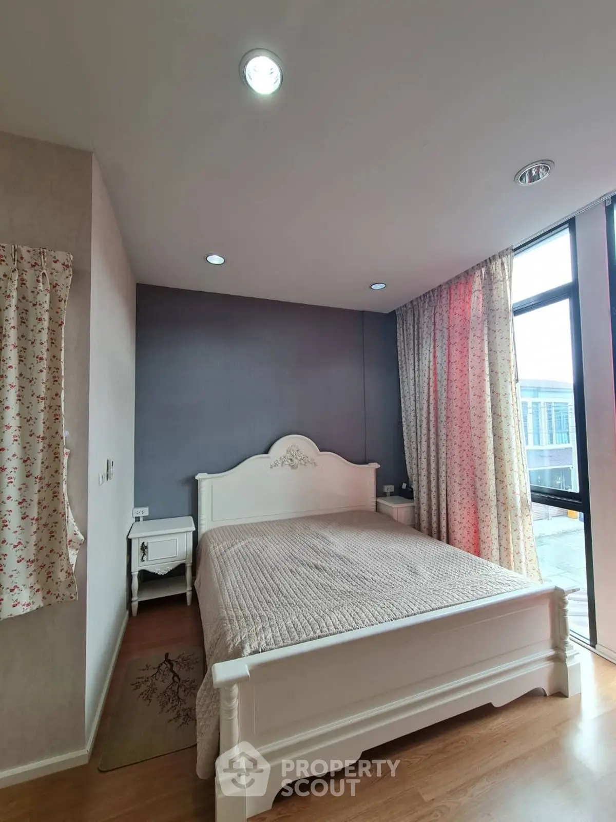 Spacious bedroom with elegant decor and large window offering natural light.