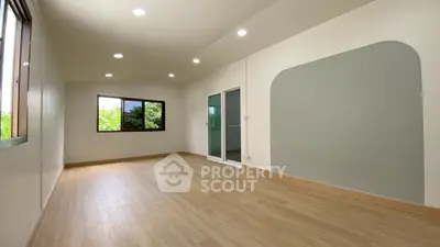 Spacious empty room with large windows and wooden flooring, perfect for customization.
