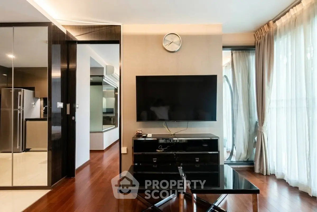 Modern living room with sleek design, large TV, and floor-to-ceiling windows for natural light.