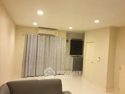 Cozy living room with modern lighting and air conditioning, featuring a small kitchenette.