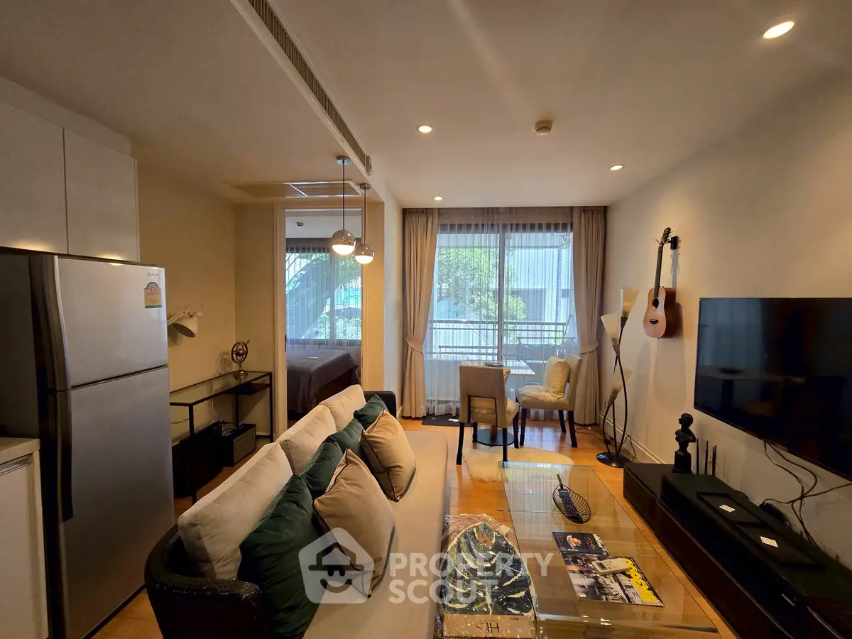 Modern living room with stylish decor, open layout, and natural light, featuring a cozy seating area and wall-mounted TV.