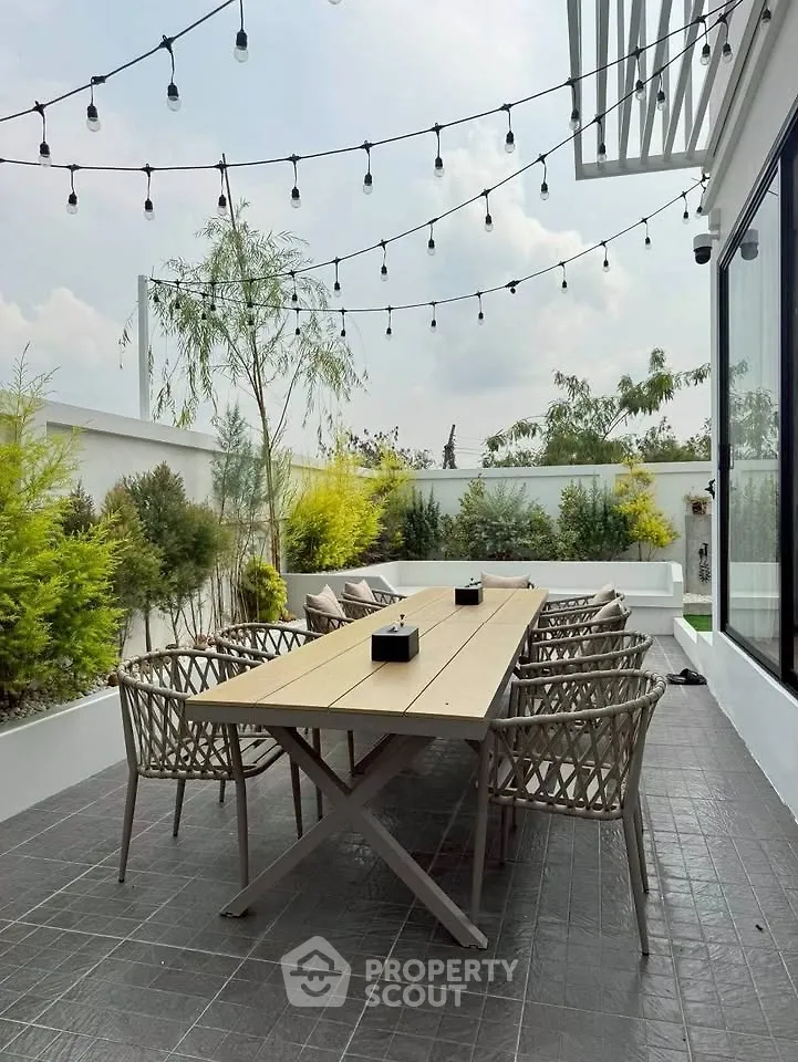Chic outdoor patio with string lights and modern dining set, perfect for entertaining.