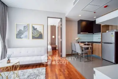 Modern open-plan living room and kitchen with elegant decor and hardwood floors.