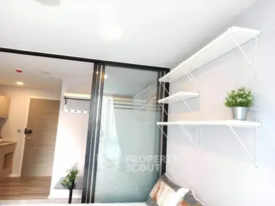 Modern bedroom with sliding glass door and wall-mounted shelves in a stylish apartment.