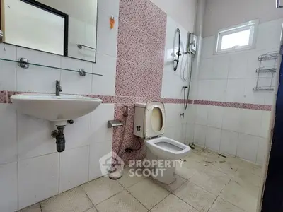 Spacious bathroom with modern fixtures and tiled walls, featuring a large mirror and ample natural light.
