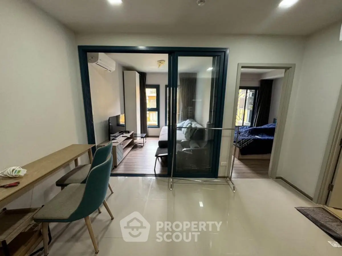 Modern apartment interior with glass partition and cozy living area.