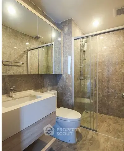 Luxurious modern bathroom with marble tiles and glass shower enclosure