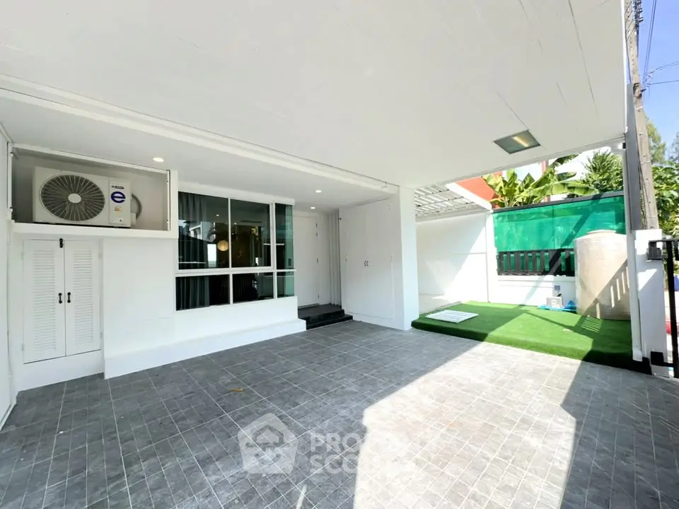 Spacious modern home exterior with covered patio and artificial grass area.