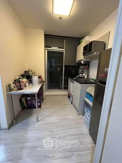 Compact kitchen with modern appliances and open layout, featuring sleek flooring and ample storage space.