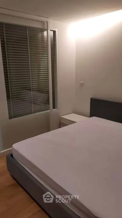Cozy bedroom with modern design and ample natural light, featuring a comfortable bed and sleek furnishings.