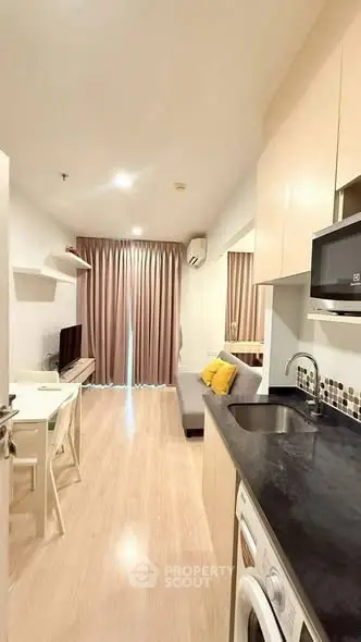 Modern studio apartment with open kitchen and cozy living area, featuring sleek design and natural light.