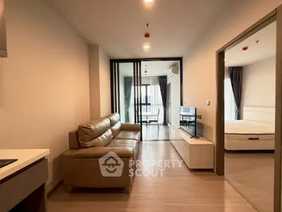 Modern apartment interior with open living room and bedroom, featuring sleek furniture and natural light.