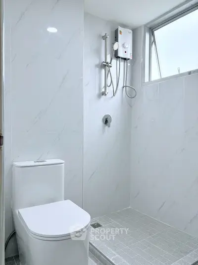 Modern bathroom with sleek white tiles and compact shower setup