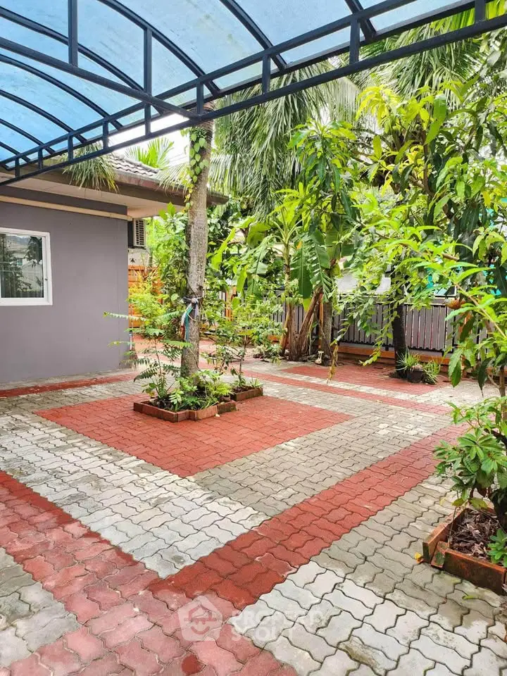 Charming garden courtyard with lush greenery and paved pathways, perfect for relaxation and outdoor activities.