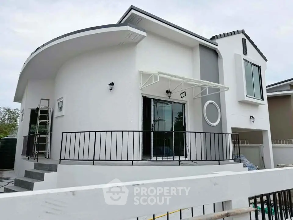 Modern white two-story house with unique curved facade and large windows, showcasing contemporary architectural design.