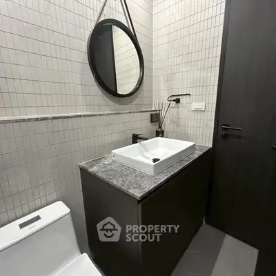Modern bathroom with sleek design, featuring a round mirror and stylish vanity.