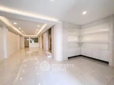 Spacious modern living room with sleek white shelves and glossy tiled flooring