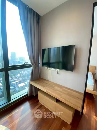 Modern bedroom with large window and wall-mounted TV, offering stunning city views.