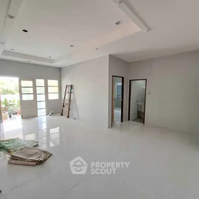 Spacious living room with large windows and glossy white flooring, perfect for modern living.