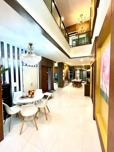 Luxurious open-plan living area with high ceilings, elegant chandelier, and modern dining set in a stylish home.