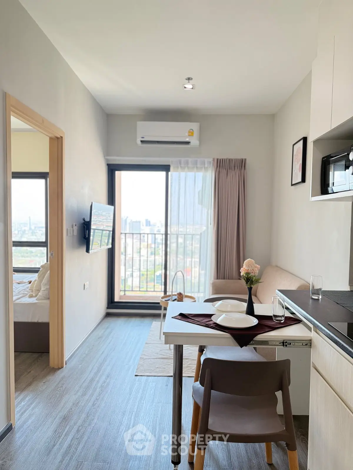 Modern apartment interior with open layout, featuring a cozy living area and dining space with city view.