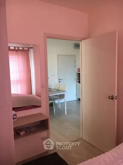 Cozy bedroom with open door leading to dining area, featuring soft lighting and modern decor.