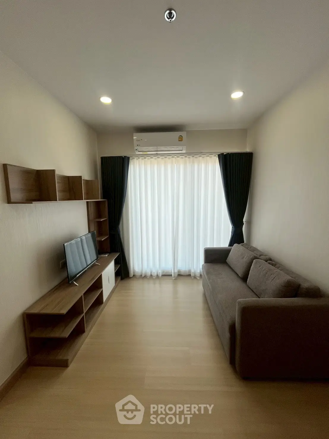 Modern living room with cozy sofa, TV unit, and large window with curtains.