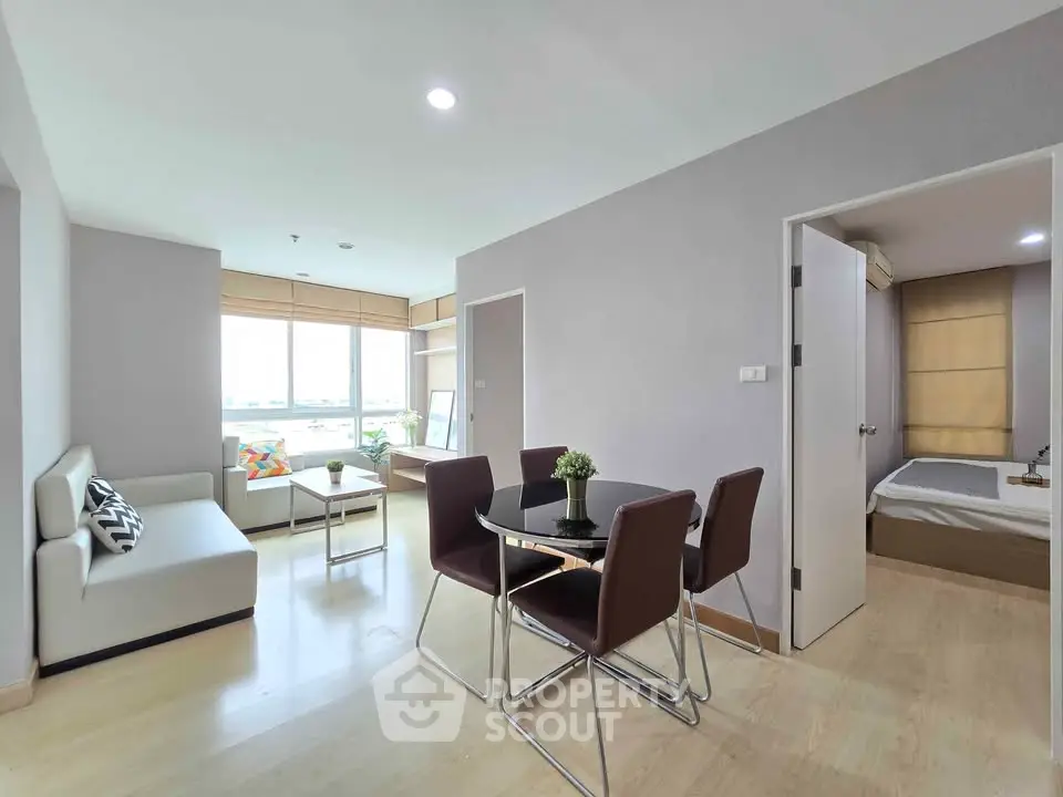 Modern apartment interior with open living and dining area, featuring sleek furniture and natural light.