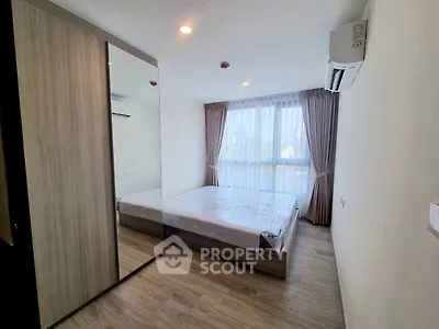Modern bedroom with large window and mirrored wardrobe in stylish apartment.