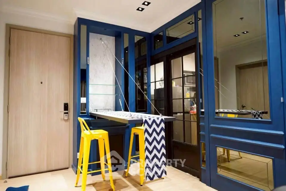 Stylish modern interior with blue accents and yellow bar stools in a compact living space.