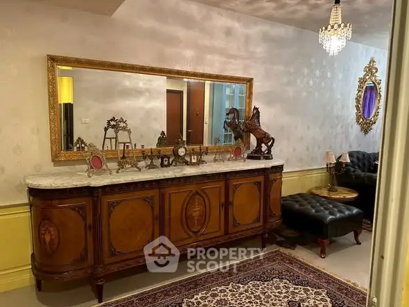 Elegant living room with vintage furniture and ornate decor, featuring a large mirror and chandelier.