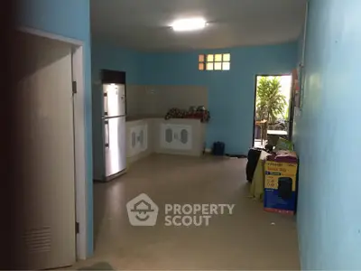Spacious kitchen area with blue walls and modern appliances, featuring a fridge and ample natural light.