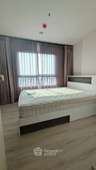 Spacious bedroom with large windows and modern decor in a high-rise apartment.