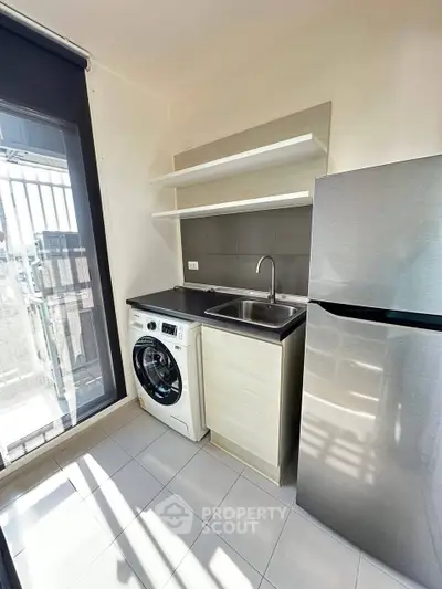 Modern kitchen with washing machine and fridge, bright natural light