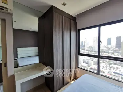 Modern bedroom with city view, featuring sleek wardrobe and large window for natural light.