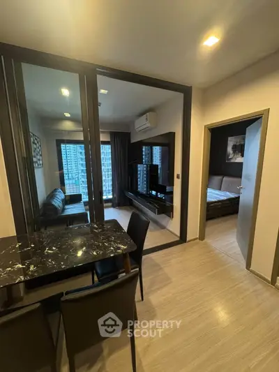 Modern apartment interior with open living and dining area, featuring sleek furniture and large windows.