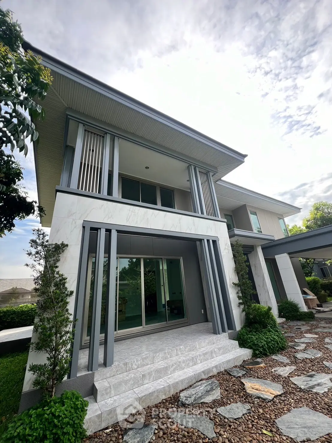 Modern two-story house with sleek design and lush landscaping