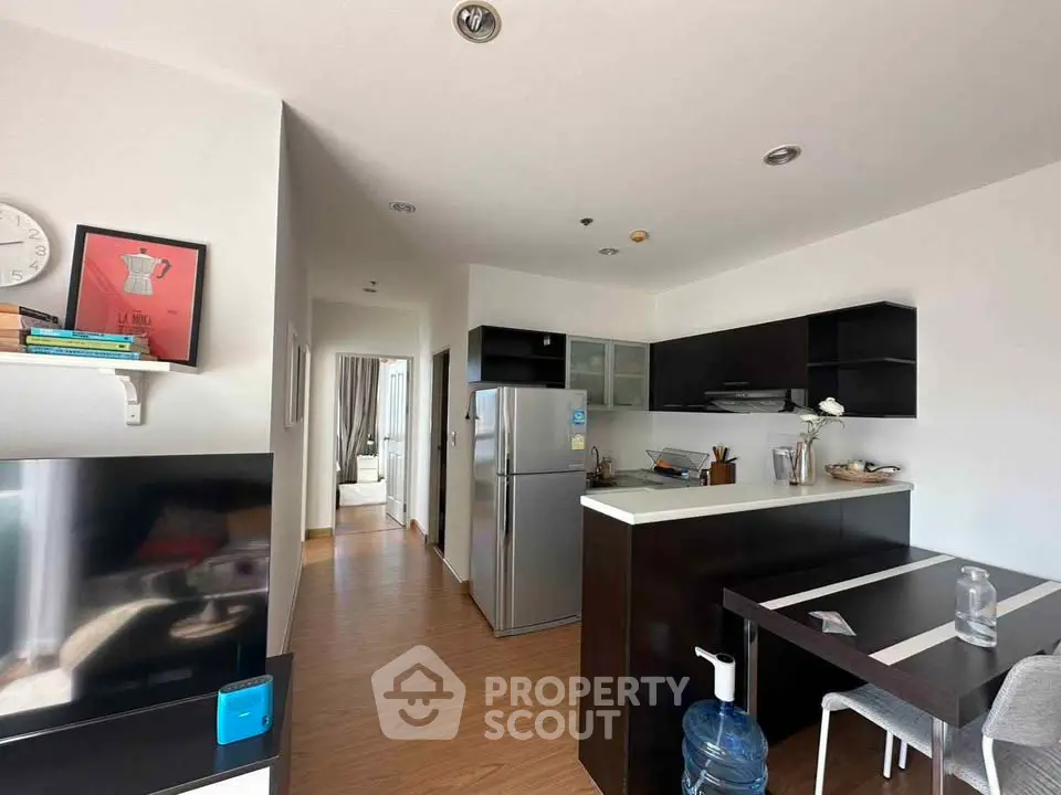 Modern kitchen with sleek black cabinets and stainless steel appliances in open layout apartment.
