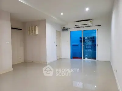 Spacious empty room with sliding glass door and bright lighting, ideal for customization.