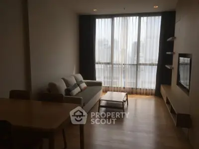 Modern living room with large windows and city view, featuring cozy sofa and sleek wooden furniture.