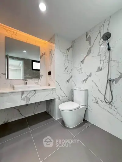 Modern bathroom with marble walls, sleek fixtures, and a spacious shower area.