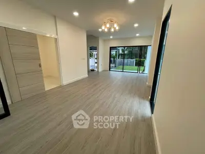 Spacious modern living room with elegant lighting and large windows overlooking a garden.