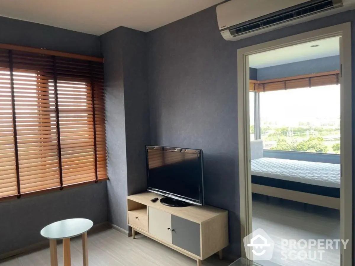 Modern living room with TV and window view into bedroom